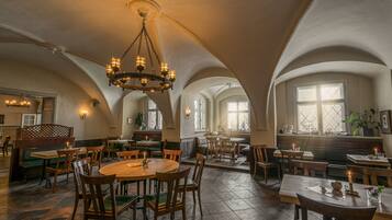 Un vaste espace dédié à la salle à manger, doté de hauts plafonds en arc et de nombreuses tables et chaises.