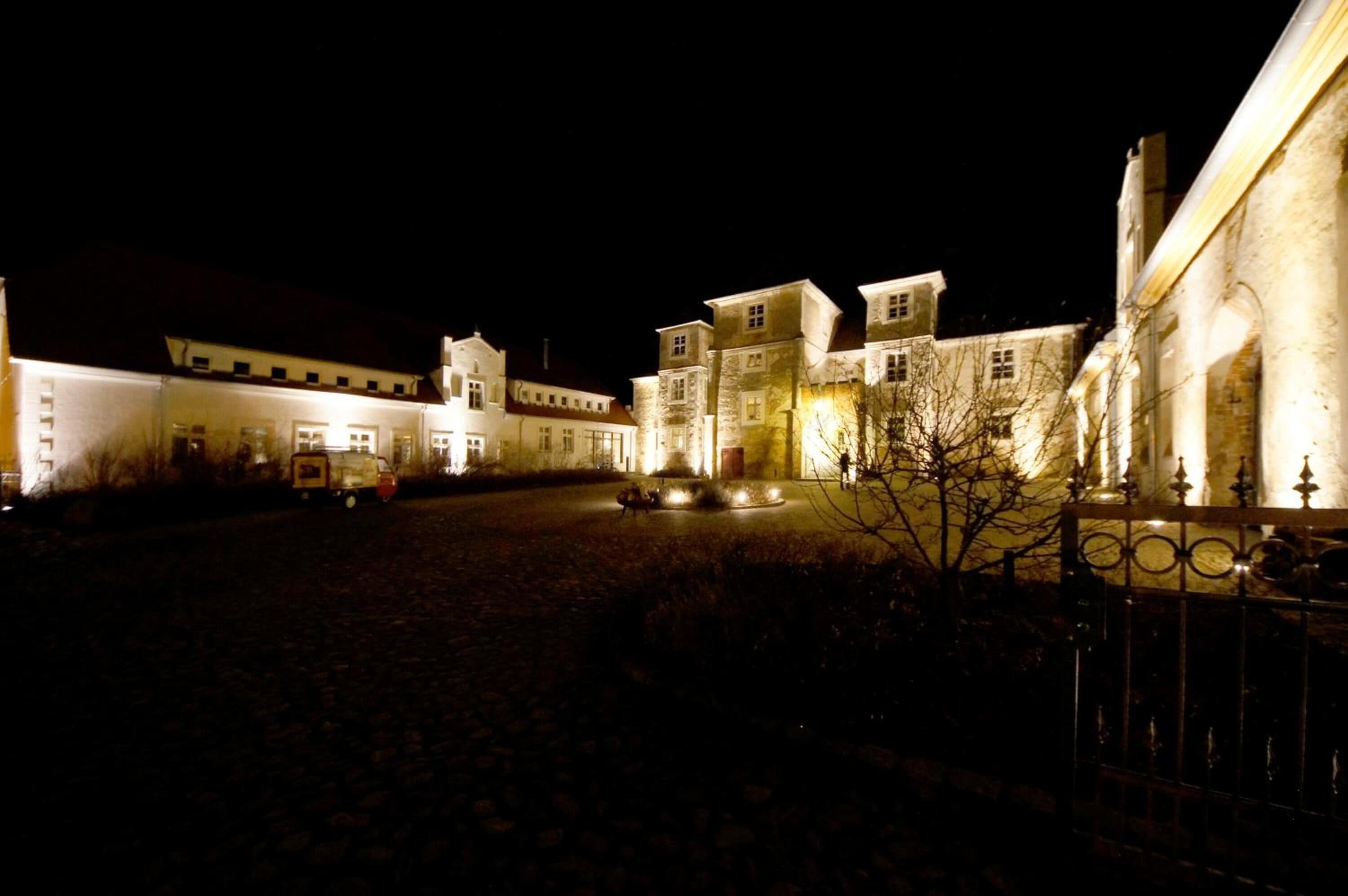 Un edificio storico con un cortile, pareti in pietra e una fontana al centro.