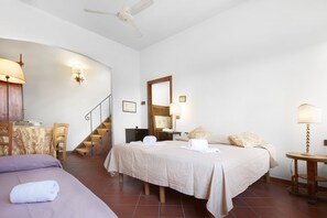 Ein Hotelzimmer mit Bett, Schreibtisch, Stuhl, einem kleinen Tisch, einer Lampe, einem Spiegel und einer Treppe.