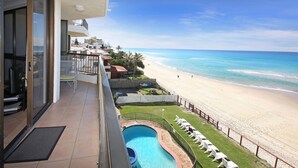 Un balcón con vista a una playa y una piscina.