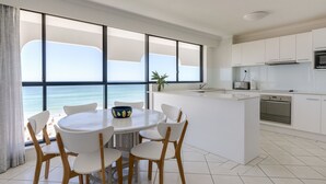 Una cocina moderna con armarios blancos, horno integrado y un amplio ventanal con vista al mar.
