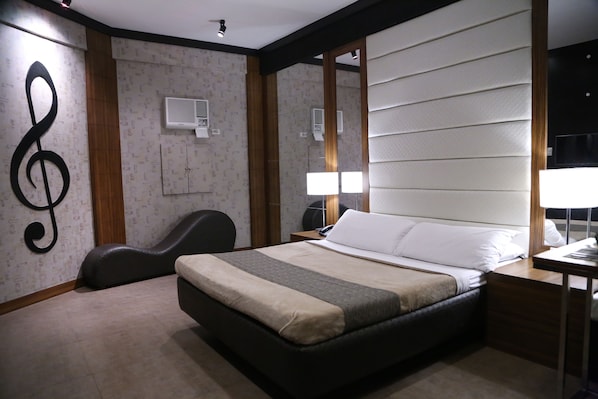 A hotel room with a bed, bedside table, lamp, and a large mirror.