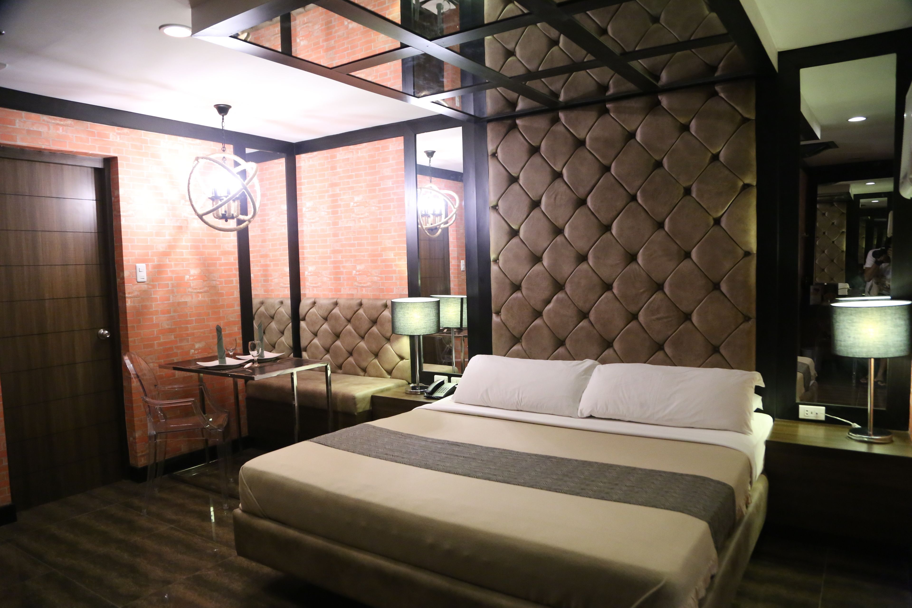 Habitación de hotel con una cama grande, un escritorio con silla, una mesita y un diseño de pared en patrón de diamantes.