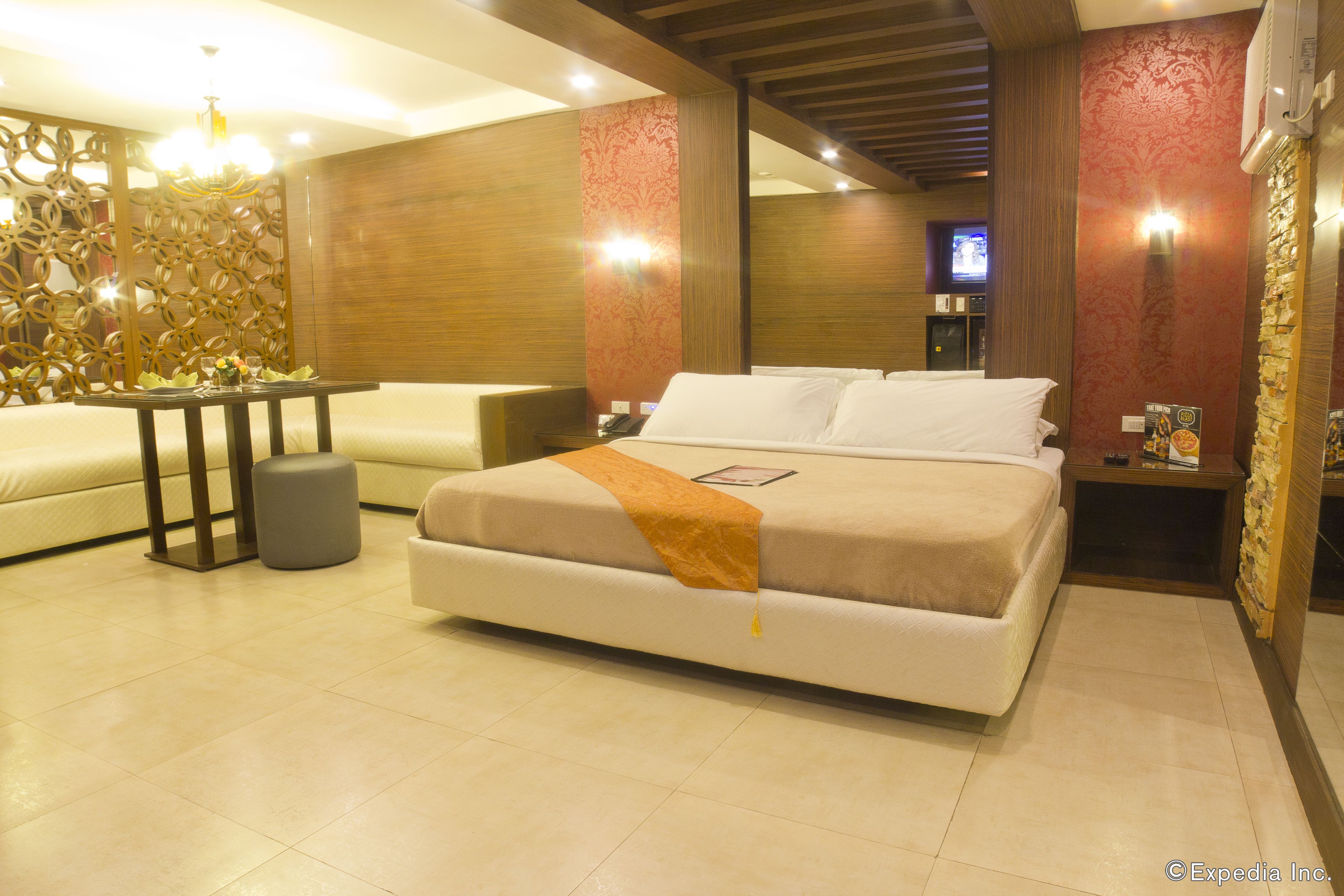Een moderne hotelkamer met een groot bed, een bank, een klein tafeltje en decoratieve wand.