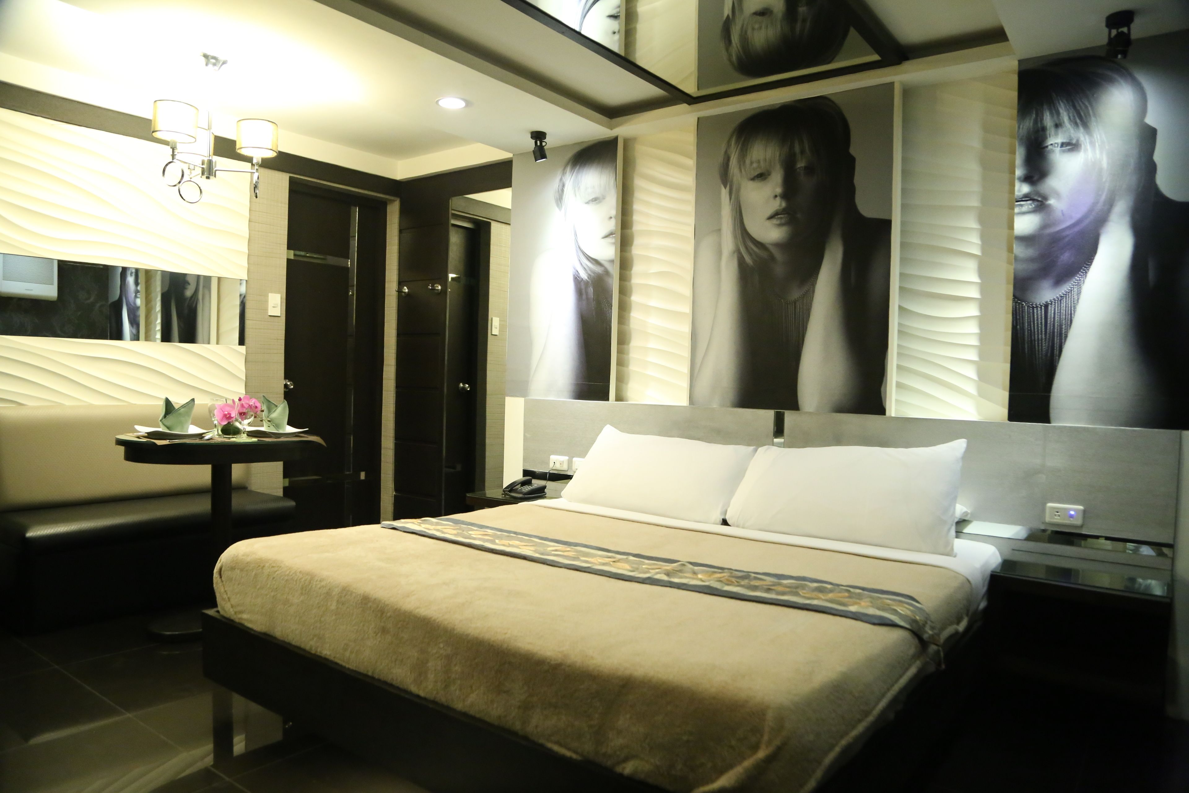 Una habitación de hotel moderna con una cama grande, mesitas de noche, un escritorio y un espejo.