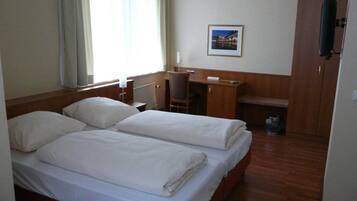 A hotel room with two beds, a desk, a chair, a wardrobe, and a picture on the wall.