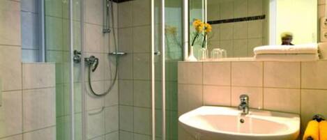 A bathroom with a glass-enclosed shower, a white sink, and a toilet.