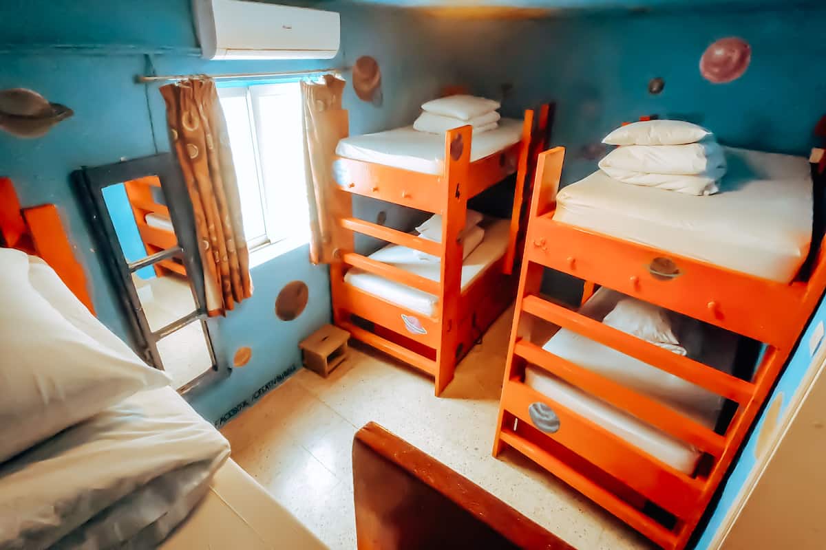 A compact room with bunk beds, a window with curtains, and a mirror.