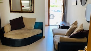 A living room with two sofas, a coffee table, a mirror, and a door leading outside. - Hostel Malti (St. Julian's)