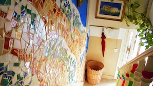 A staircase with a mosaic wall, a wicker basket, and a red umbrella. - Hostel Malti (St. Julian's)