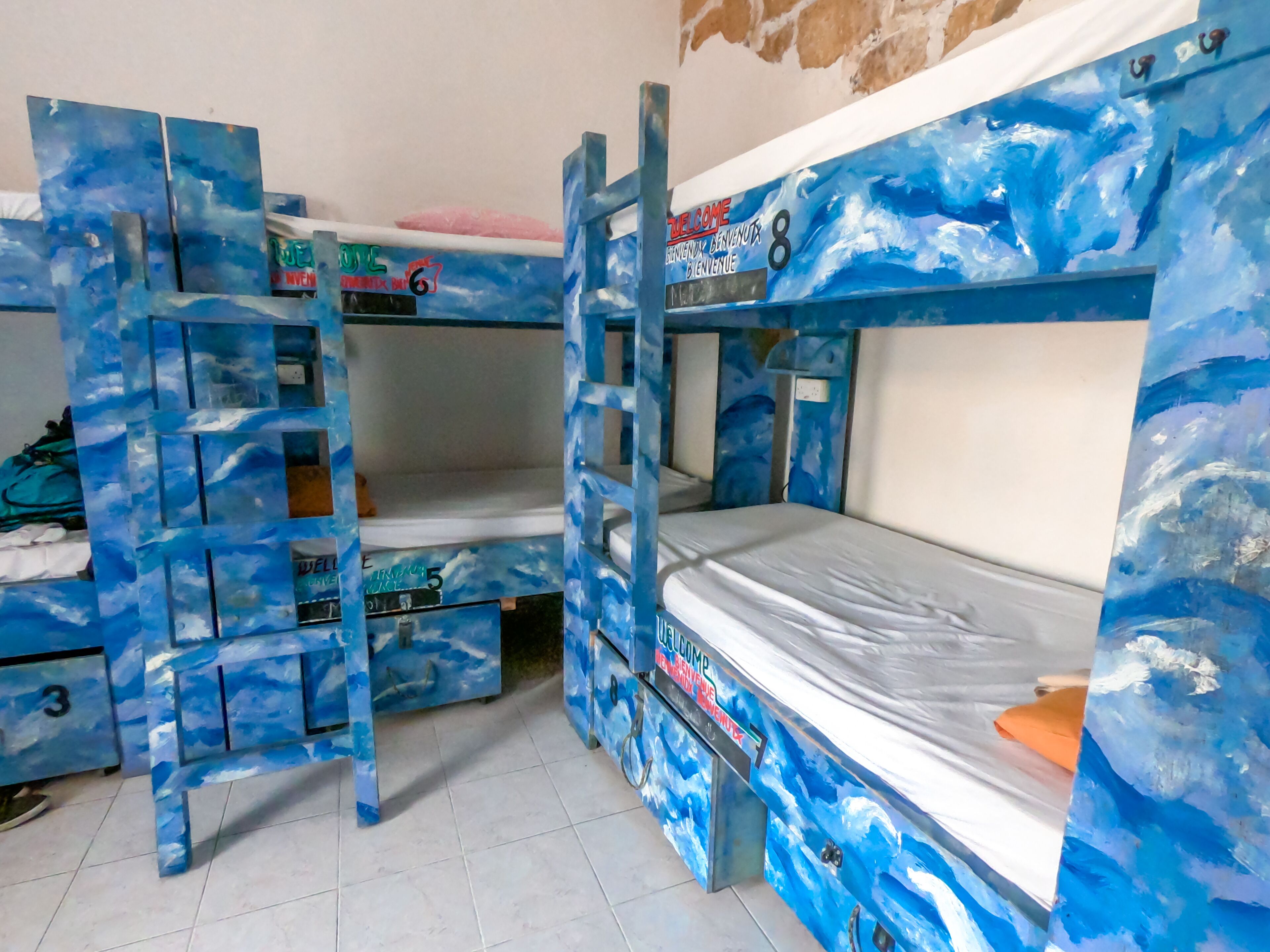 A bunk bed room with a blue ocean-themed design, including a ladder and a small desk.