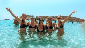 A group of people in a clear blue pool with rocky hills in the background. - Hostel Malti (St. Julian's)