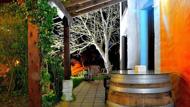 Un área de patio al aire libre con un barril de madera, sillas y un camino empavedado.