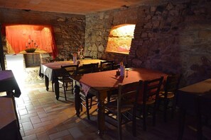 A rustic dining area with stone walls, wooden tables, and chairs. - Hotel Due Colonne (San Bonifacio)