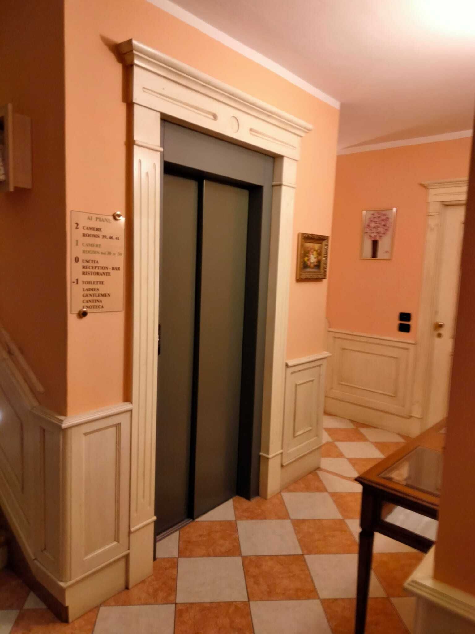 A hotel corridor with an elevator, a reception area, and a check-in counter.
