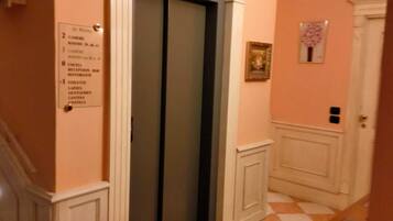 A hotel corridor with an elevator, a reception area, and a check-in counter.