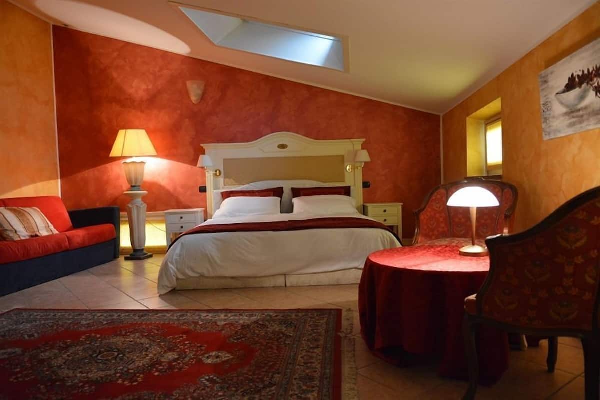 A bedroom with a bed, a nightstand, a chair, a table, and a lamp.