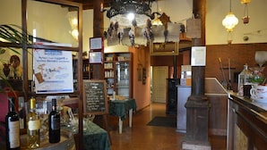 A bar area with a wooden barrel, wine bottles, a chalkboard menu, and a hanging floral decoration. - Hotel Due Colonne (San Bonifacio)