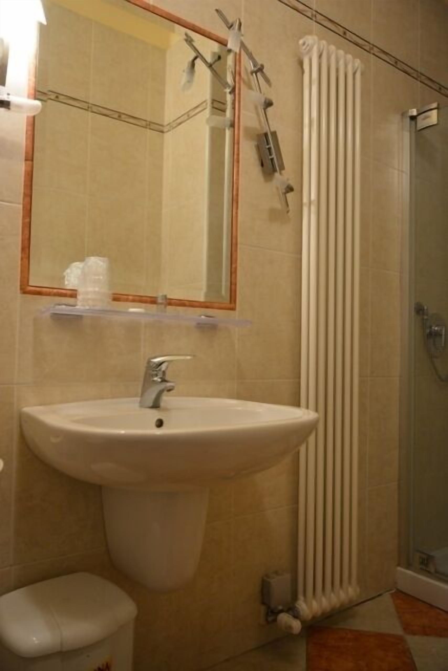 Baño con lavamanos, inodoro y cabina de ducha de vidrio.