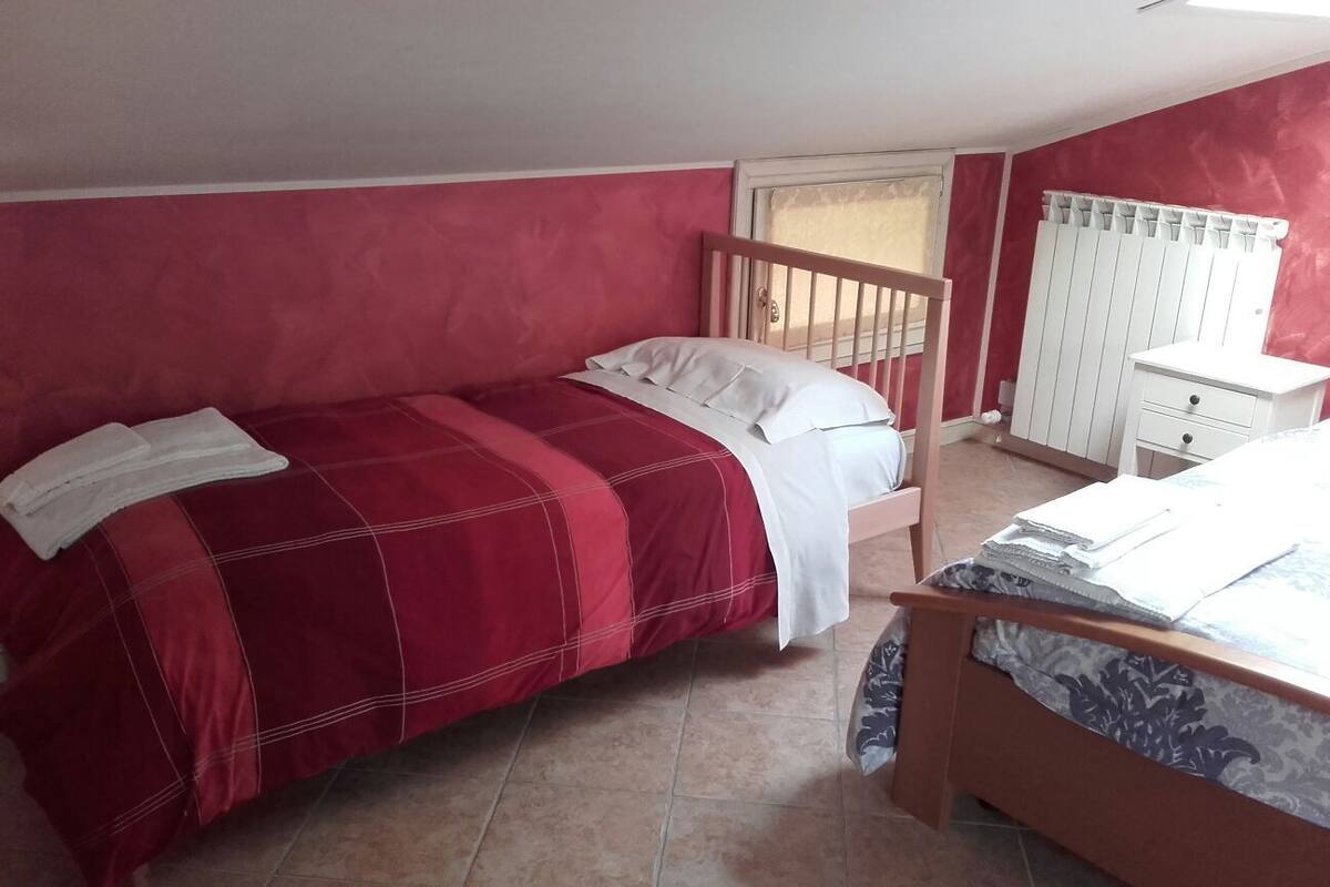 A bedroom with two beds, a window, a radiator, and a white dresser.