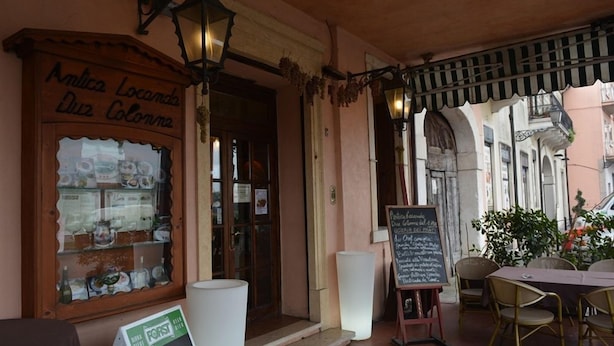 An outdoor cafe with a wooden signboard, a chalkboard menu, and a table with chairs. - Hotel Due Colonne (San Bonifacio)