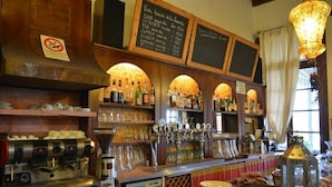 A bar area with espresso machines, a variety of bottles, and a chalkboard menu. - Hotel Due Colonne (San Bonifacio)