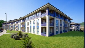 A multi-story hotel with balconies, a parking lot, and a well-maintained lawn.