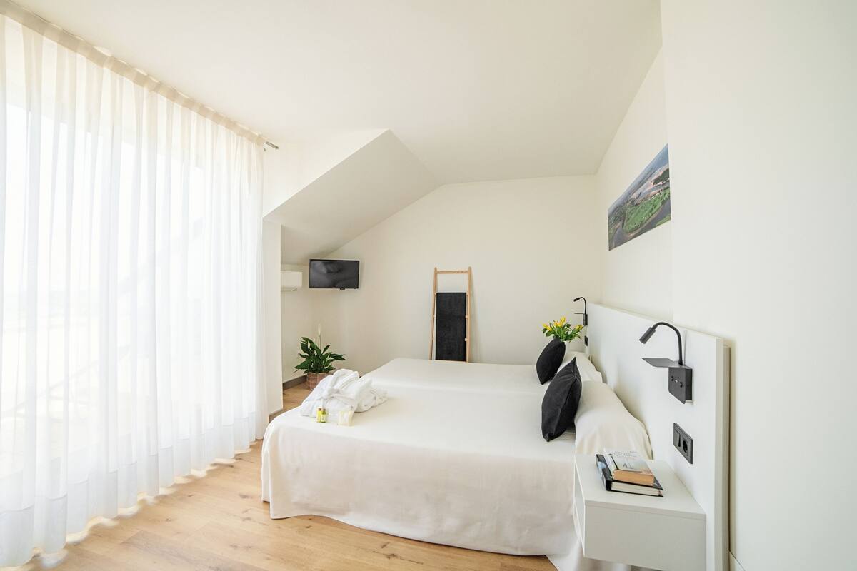 Een slaapkamer met een bed, nachtkastje en een aan de muur bevestigde televisie.
