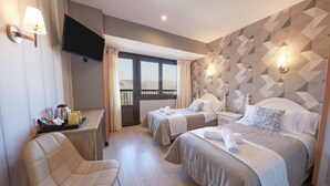 A hotel room with two beds, a TV, a desk with a chair, and a view of the outdoors. - Hotel Sánchez (Ainsa)
