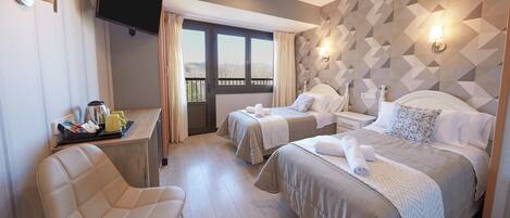 A hotel room with two beds, a TV, a desk with a chair, and a view of the outdoors.