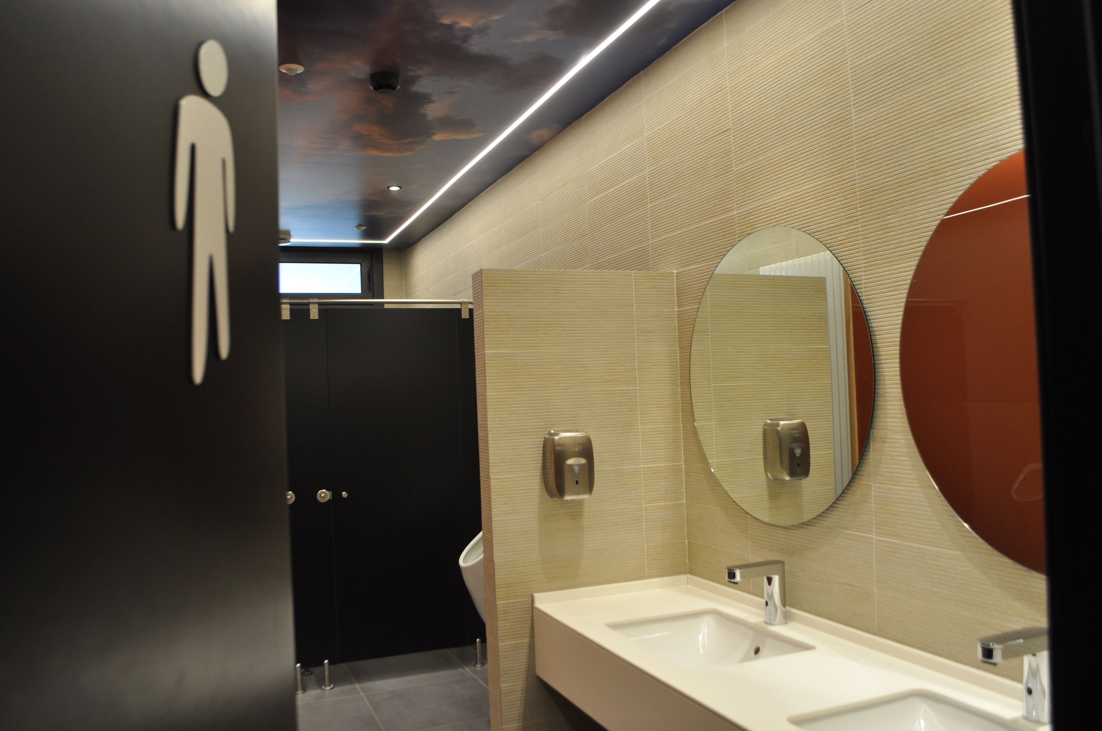 A modern bathroom with a large mirror, a sink, and a urinal.