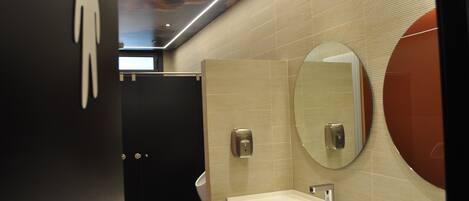 A modern bathroom with a large mirror, a sink, and a urinal.