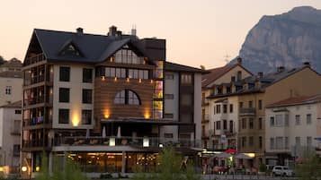 A multi-story hotel with balconies, large windows, and a mountain backdrop.