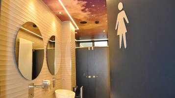 Un baño moderno con diseño de techo estrellado, un espejo grande y un dispensador de papel higiénico.