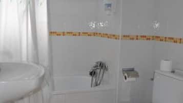 Un baño con lavamanos, inodoro y bañera blancos.
