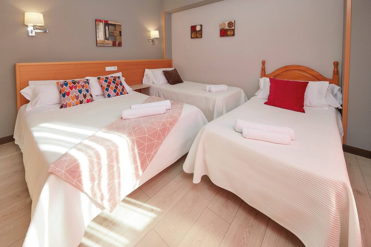 A hotel room with two beds, each with a white bedspread and pillows, and a wooden headboard.
