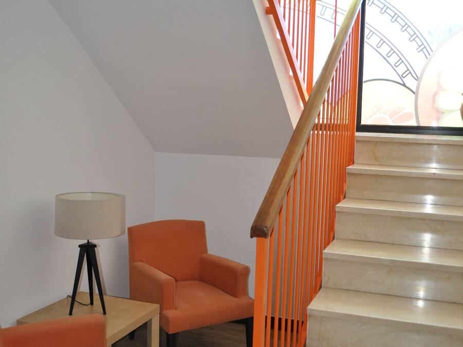 A modern interior with a staircase, orange furniture, and a lamp.