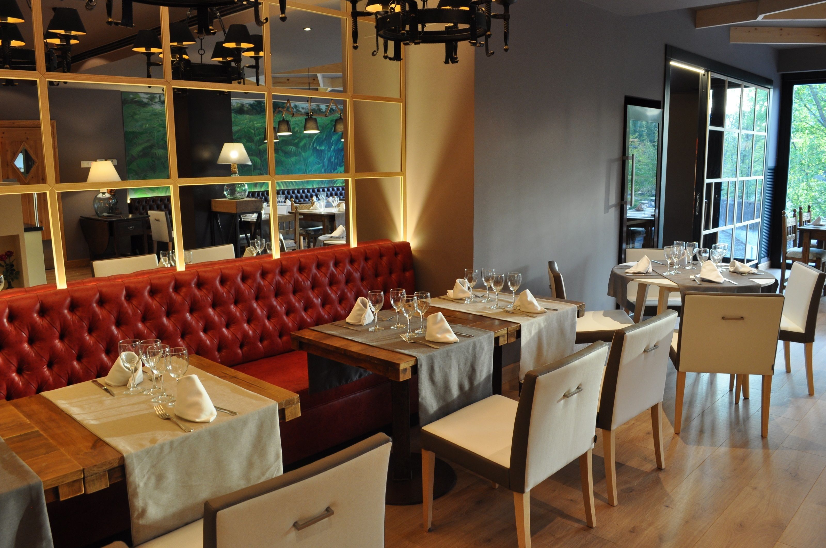 Un restaurante con un banco acolchado rojo, mesas y sillas de madera.