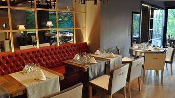 Un restaurante con un banco acolchado rojo, mesas y sillas de madera.