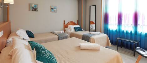 Habitación de hotel con dos camas, un banco, un espejo y obras de arte en la pared.