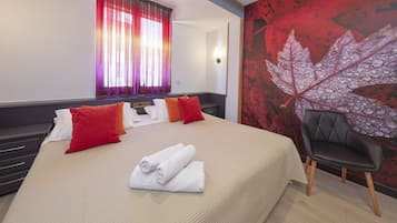 A hotel room with a bed, pillows, a chair, and a wall with a leaf design.