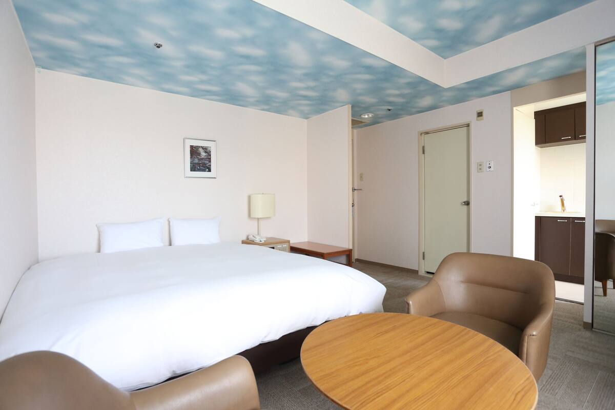 Una habitación de hotel con una cama grande, un escritorio, una silla y una mesa redonda.