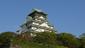 A traditional Japanese castle with multiple tiers, surrounded by lush greenery. - Hotel International House Osaka (Osaka)