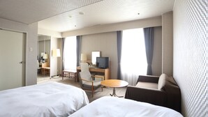 A hotel room with two beds, a desk with a computer, a chair, a small table, and a TV. - Hotel International House Osaka (Osaka)