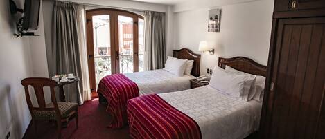 Ein Hotelzimmer mit zwei Betten, einem Schreibtisch mit Stuhl, einem Fernseher und einem Kleiderschrank.