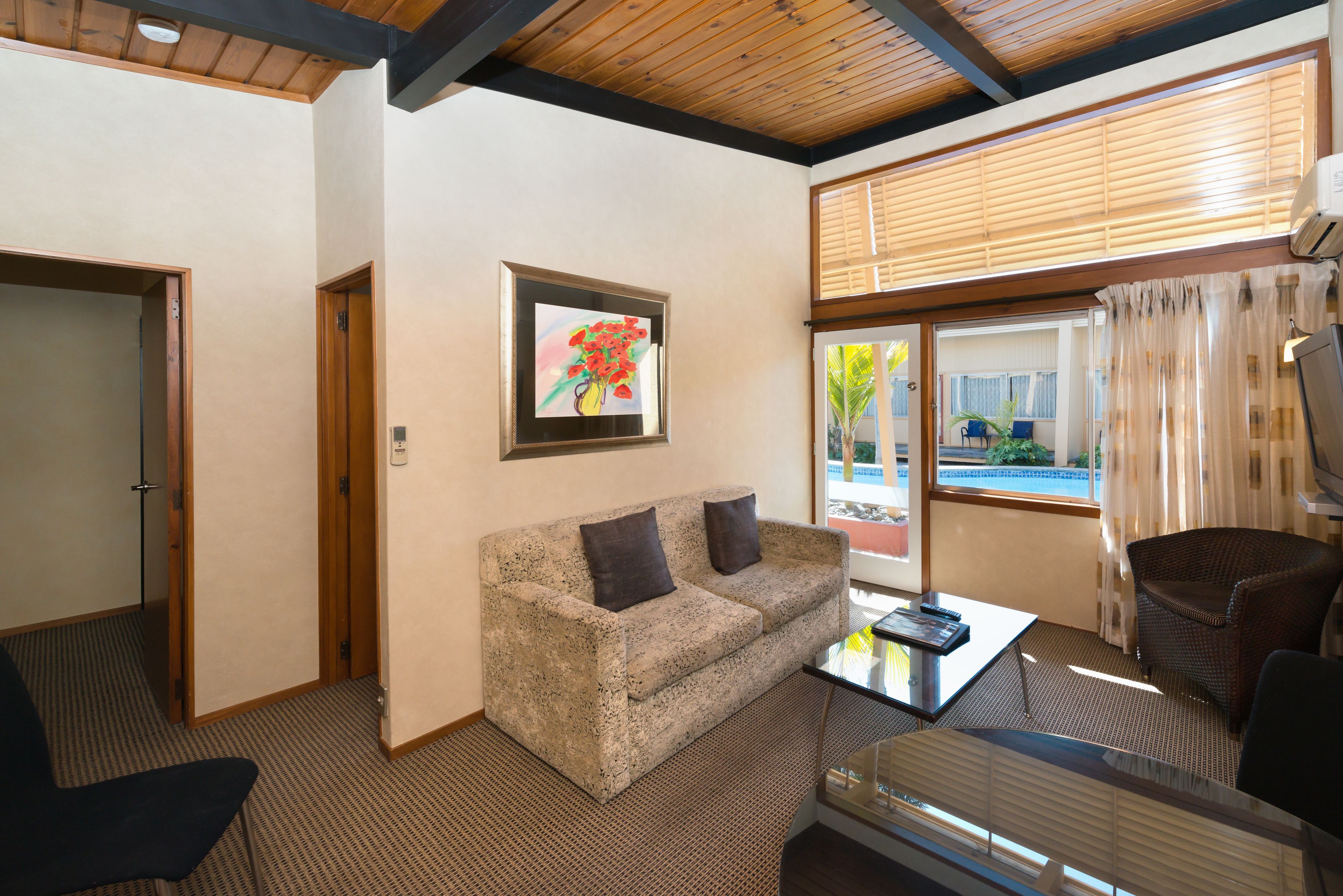 A room with a sofa, a table, a chair, and a window with blinds.