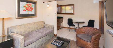 A living room with a sofa, a coffee table, a wicker chair, a TV, and a framed picture on the wall.