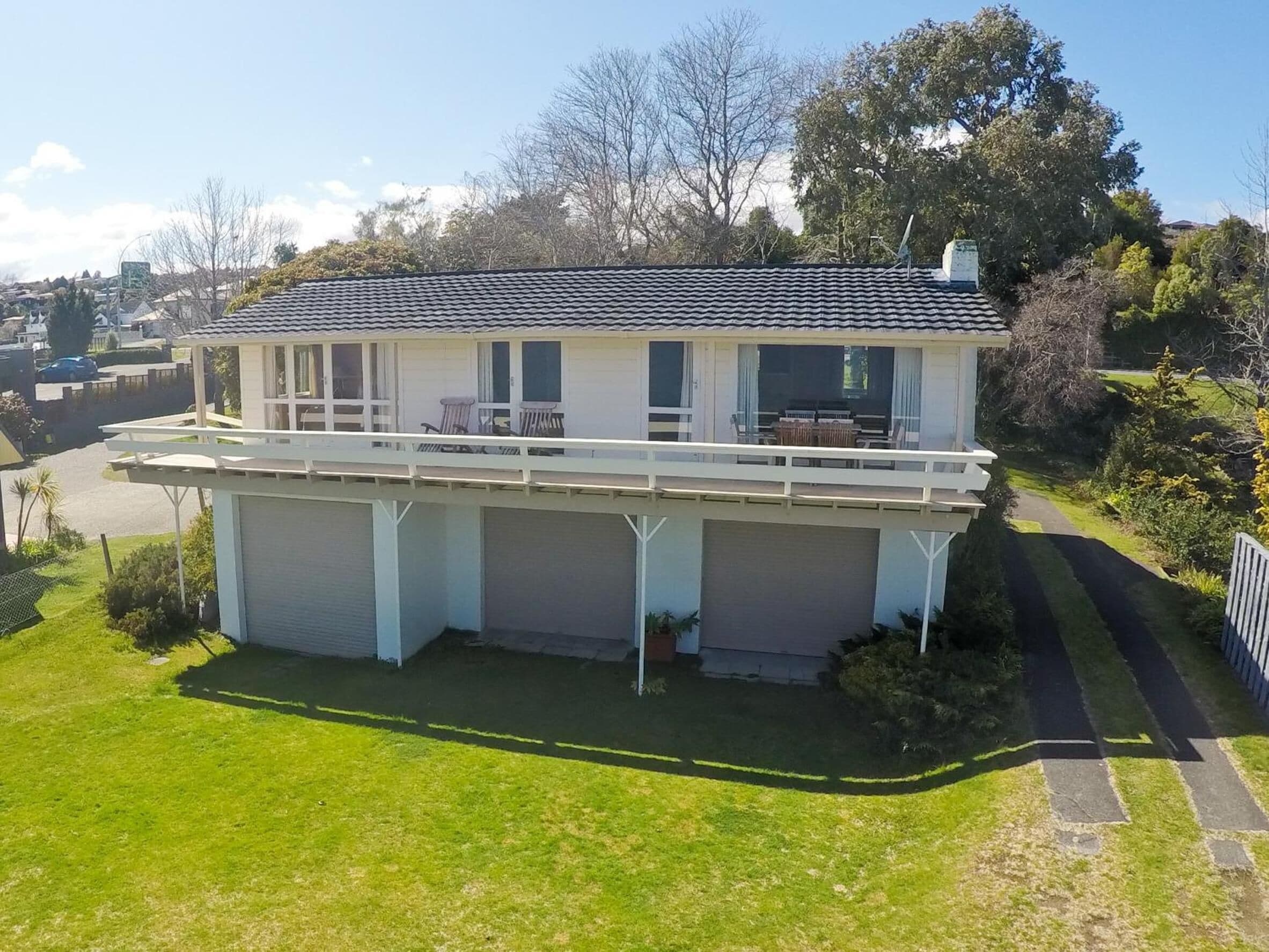 A two-story house with a balcony, a garage, and a well-maintained lawn.