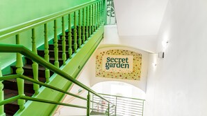 A staircase with green railings leading to a landing with a sign that reads "secret garden". - The Secret Garden Apartments (Kraków)