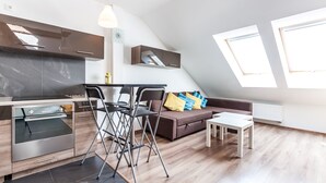 A modern kitchen with a built-in oven and a dining area with a table and chairs. - The Secret Garden Apartments (Kraków)